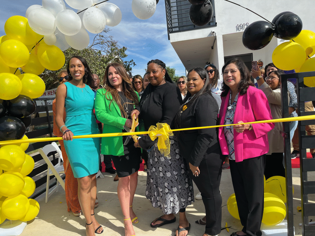 POWR event: Women cutting ribbon at building opening with balloons.