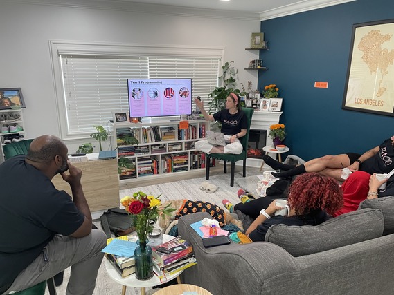 Group watches presentation on "Year 1 Programming" in a living room