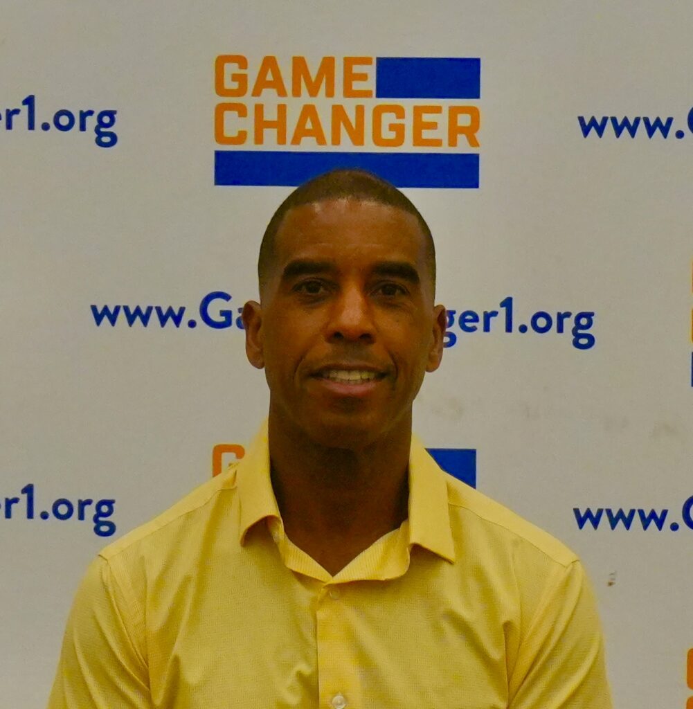 Man in yellow shirt in front of Game Changer logo