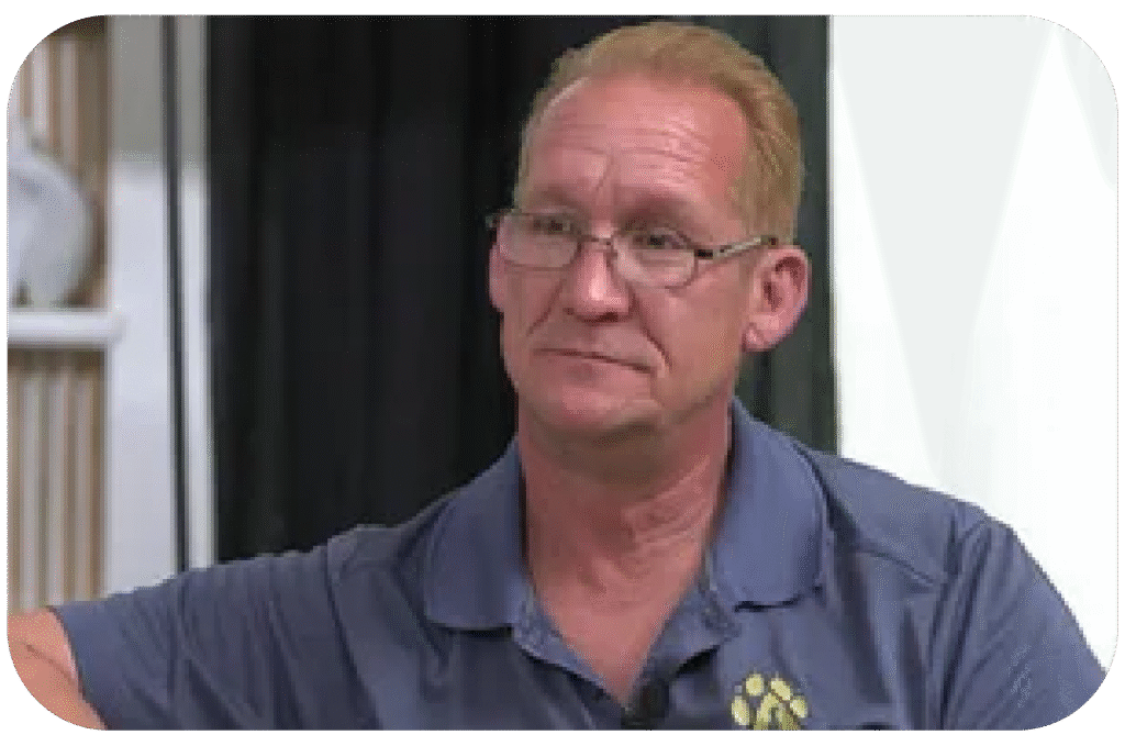 Man with glasses and a blue polo shirt with a paw print logo.